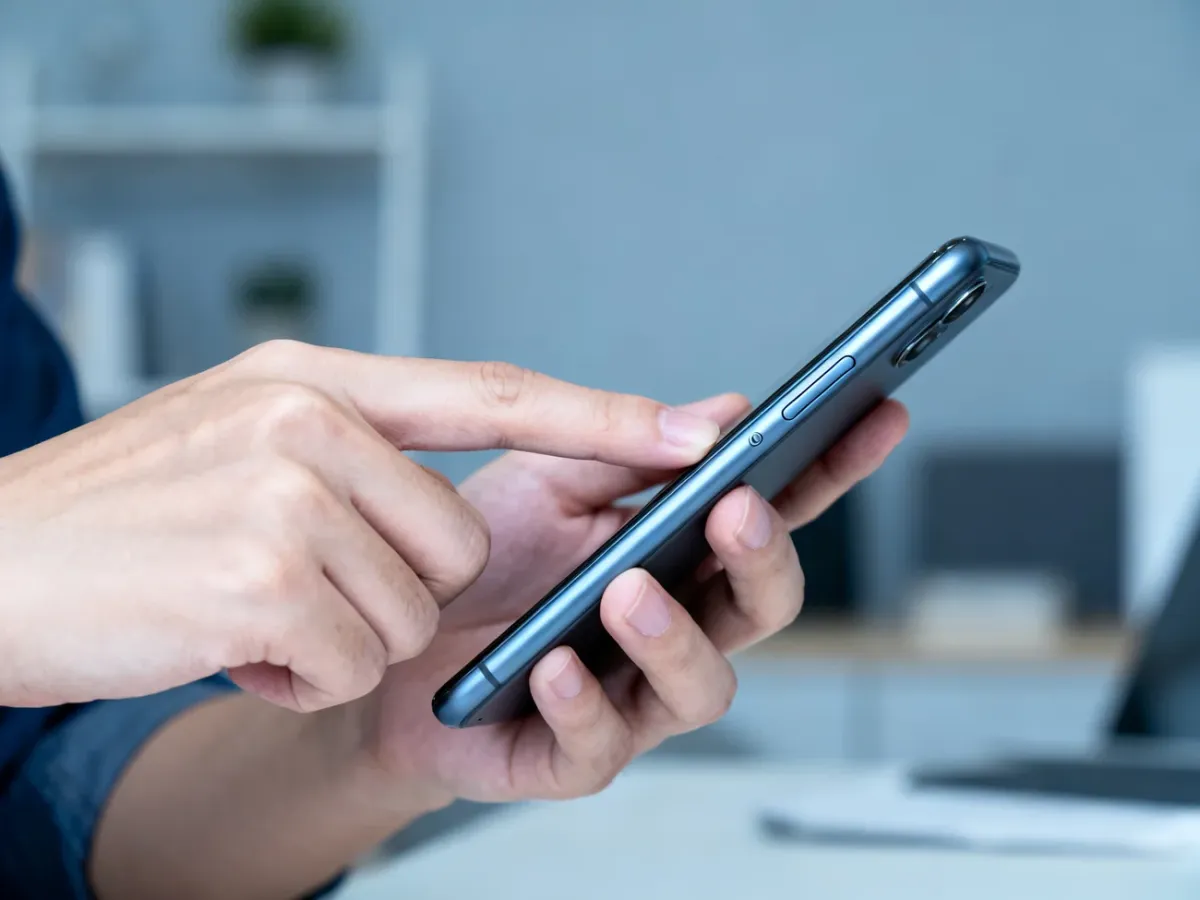 Dłonie wymuszające restart smartfona za pomocą przycisków zasilania i głośności